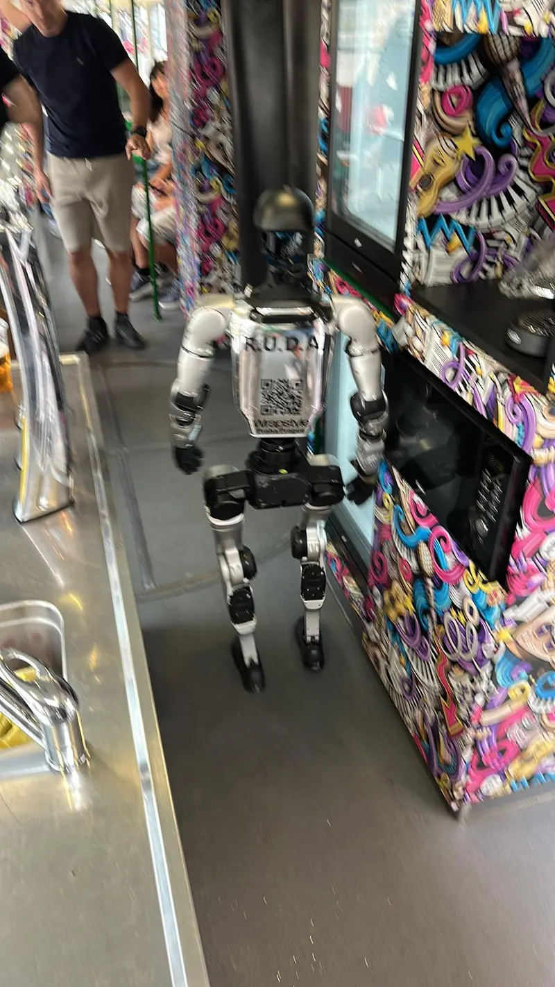 Humanoid prochází uličkou vyhlídkové tramvaje