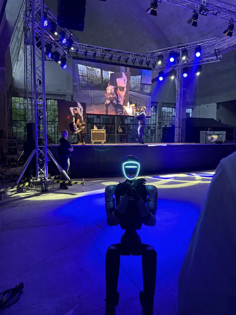 Humanoid stojí v hledišti před osvětleným pódiem