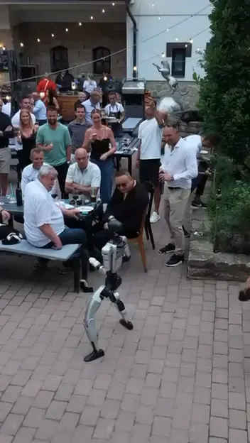 Humanoid tančí před hosty u stolů na terase