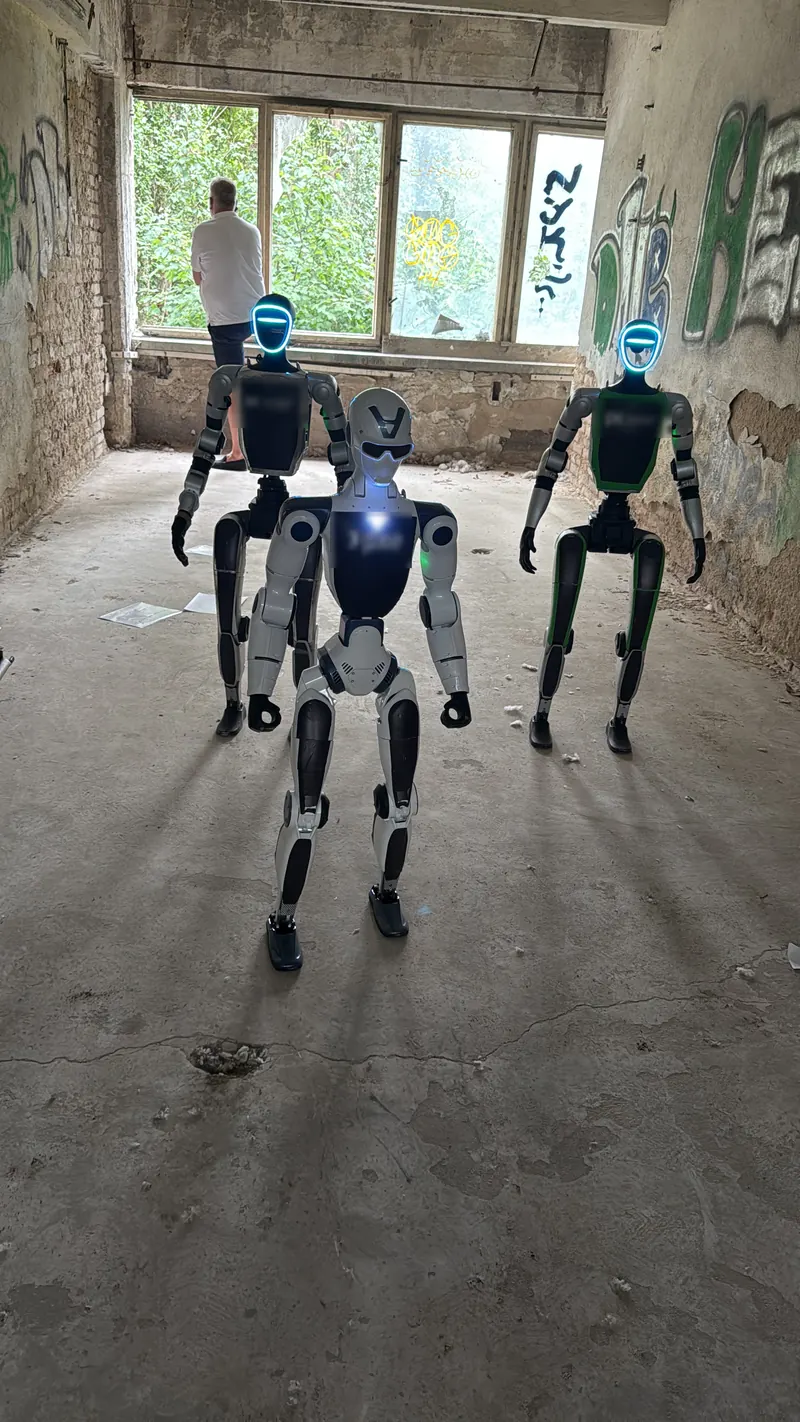 Tři humanoidní roboti přicházejí industriální halou